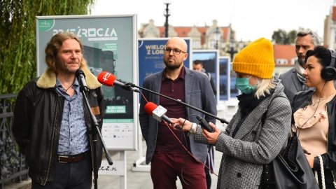 Maciej Cuske pokazuje fotosy z filmu Wieloryb z Lorino. Na moście w Bydgoszczy